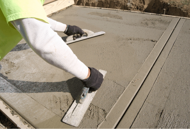 Skilled concrete contractor smoothing freshly poured concrete for a public sidewalk